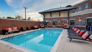 Une piscine avec des chaises longues et un mur en briques.