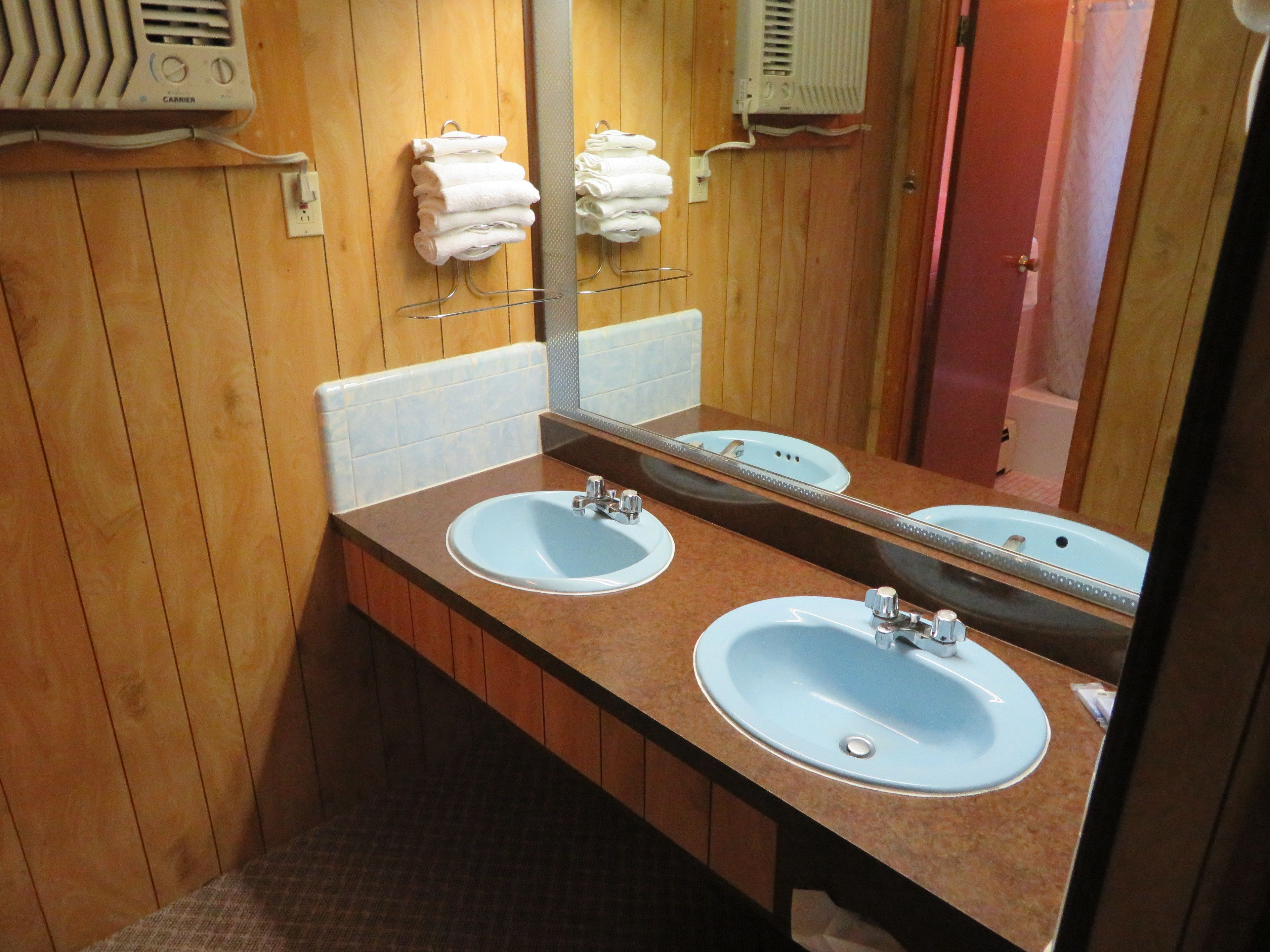A bathroom with wooden walls, two sinks, a mirror, and towel racks.