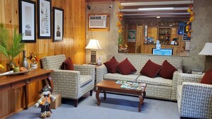 A cozy lobby with patterned sofas, a wooden reception desk, and a mirror reflecting the interior. - Red Ranch Motel (Catskill)