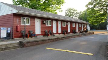 A red motel with multiple rooms, a covered outdoor seating area, and a parking lot.