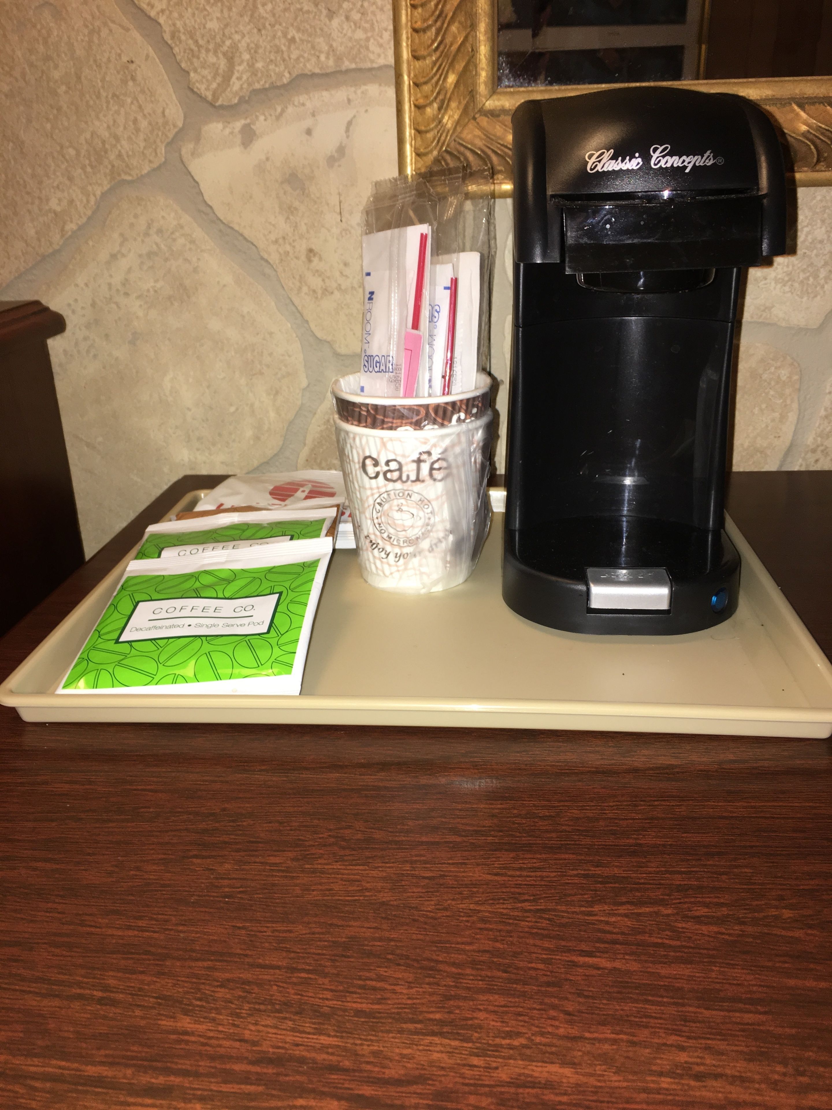 Una cafetera, un recipiente con cápsulas de café y una bandeja con objetos relacionados al café.