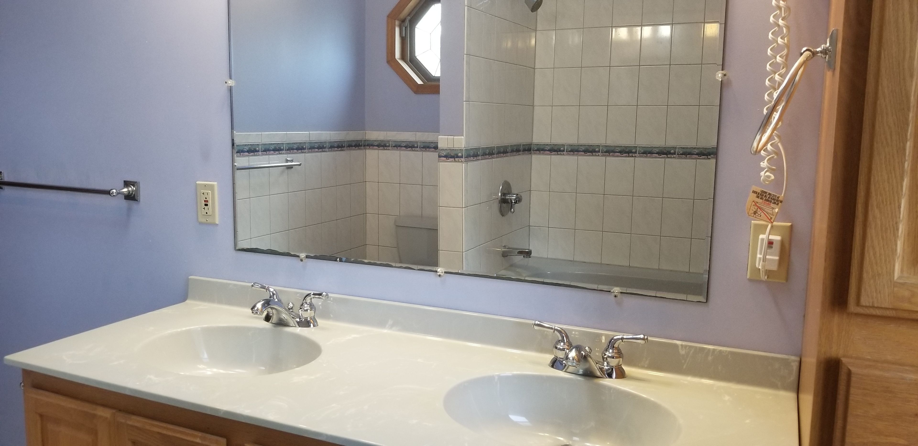 Une salle de bain avec deux lavabos, un miroir et un porte-serviettes.