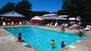 A swimming pool with lounge chairs and a red building in the background. - Red Ranch Motel (Catskill)