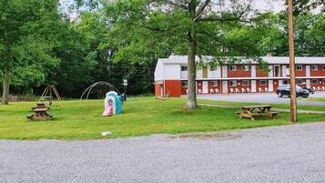 A motel with a red and white exterior, picnic tables, a playground, and a parking area.
