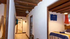 Un dormitorio con cama, un banco de madera, una lámpara colgante y vistas al baño.