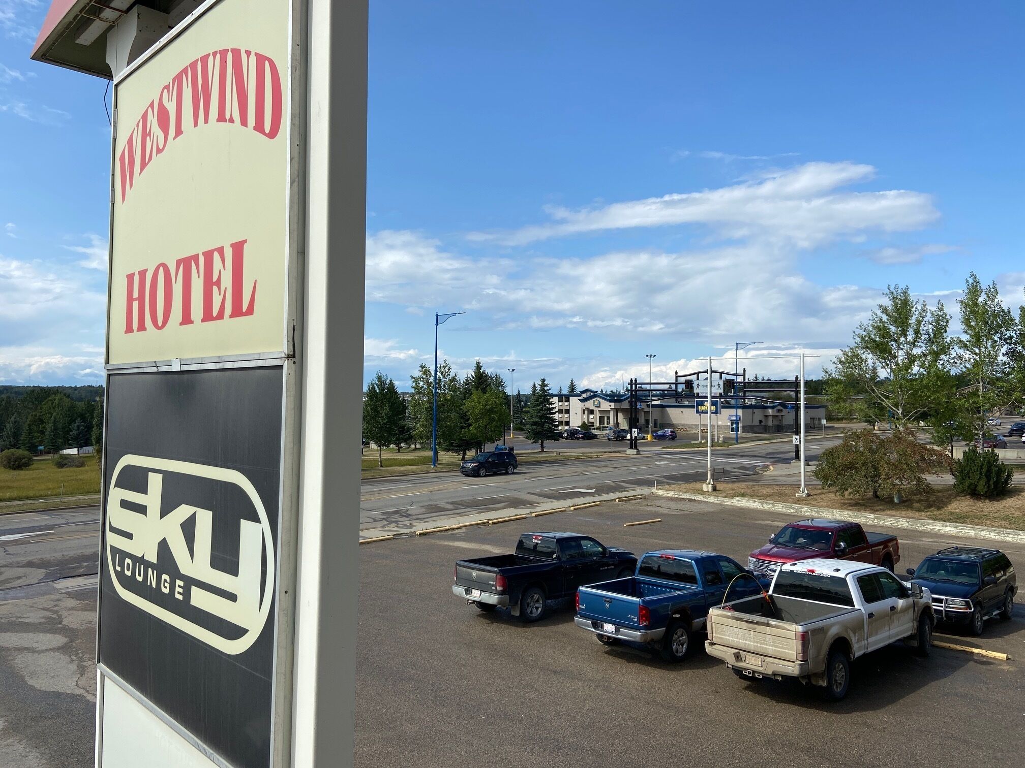 Schild des Westwind Hotels mit einem Parkplatz voller Lastwagen.