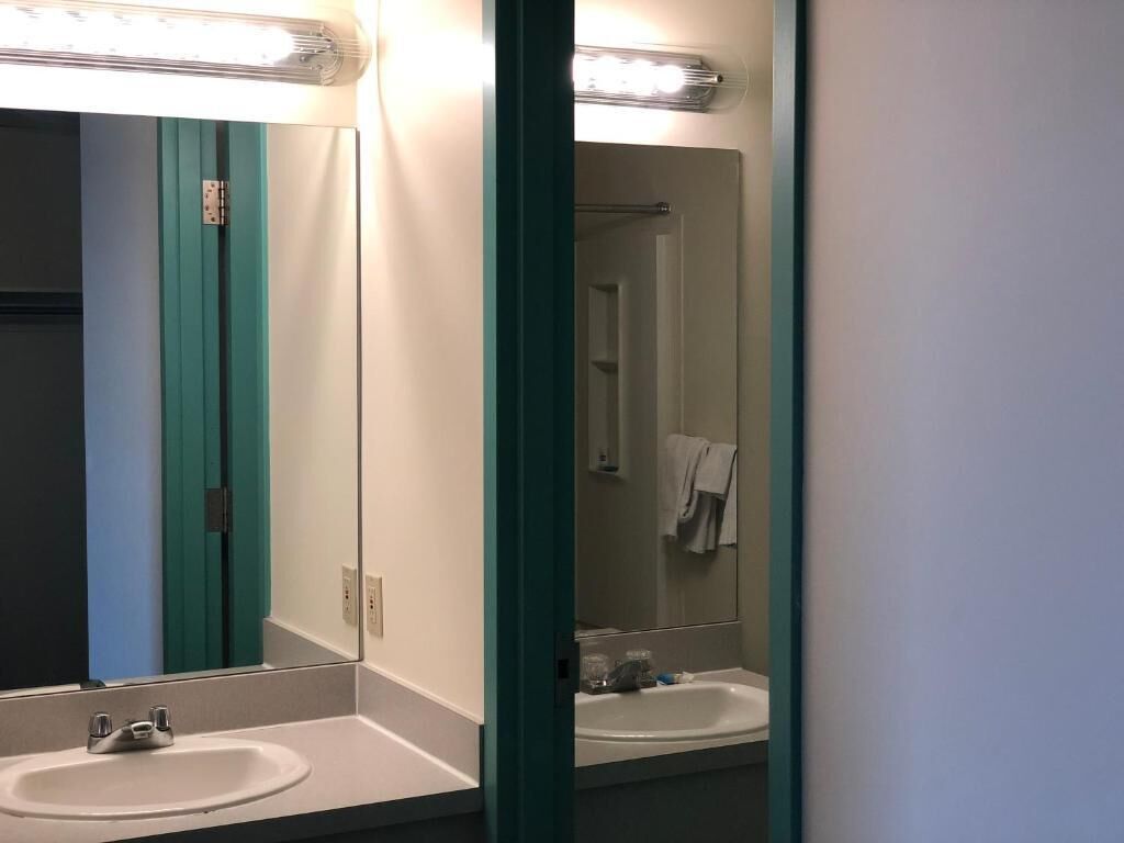 A bathroom with a white sink, a mirror, and a green door frame.
