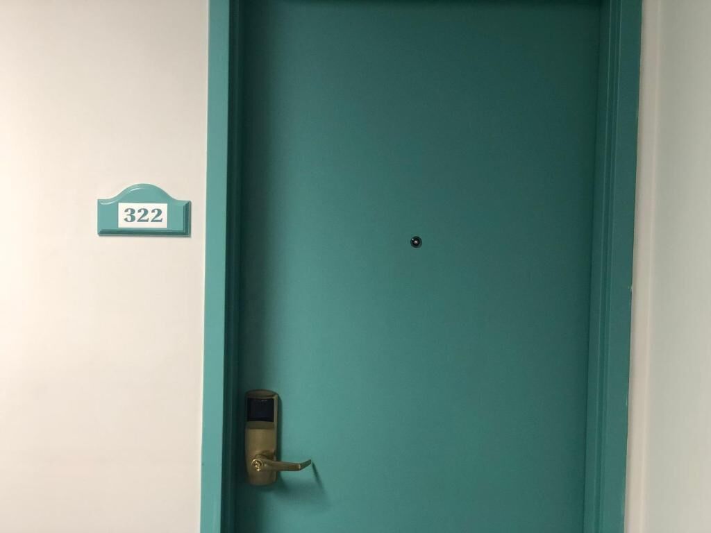 Una puerta color turquesa con una cerradura y una placa que indica la habitación 322.