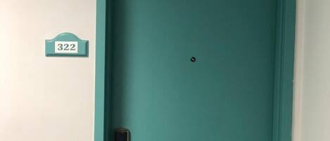 Una puerta color turquesa con una cerradura y una placa que indica la habitación 322.