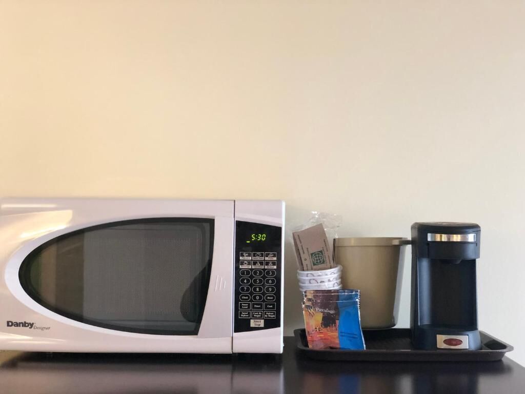 A microwave, a coffee maker, and a tray with items on a countertop.