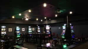 Una sala tenuemente iluminada con varias máquinas de juego y mesas.