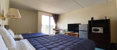 A hotel room with two beds, a television, a refrigerator, and a microwave.