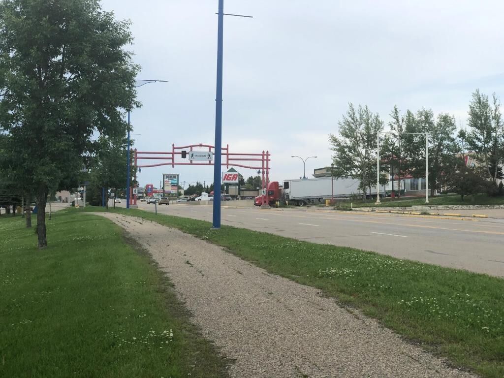 A road intersection with a pedestrian crossing, a gravel path, and a grassy area.