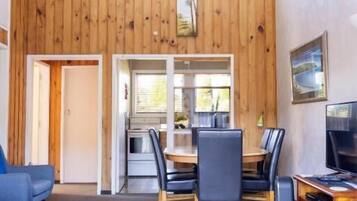 Un comedor con una mesa y sillas de madera, un televisor y un sofá.