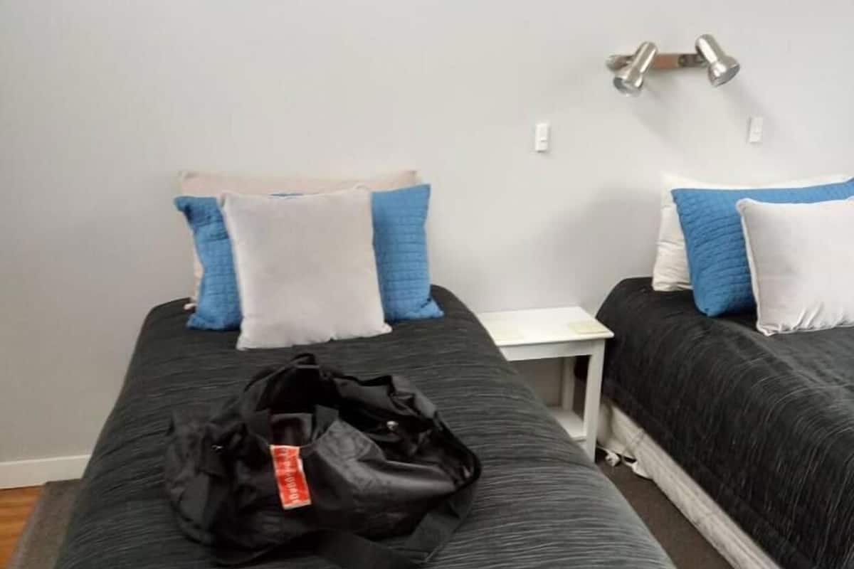 A hotel room with a single bed, a small bedside table, and a wall-mounted lamp.