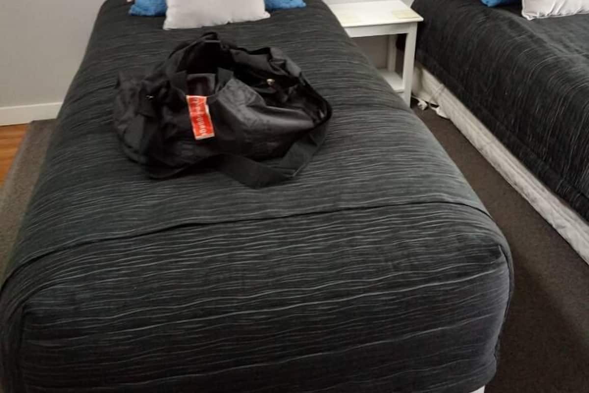 A hotel room with a large bed, a smaller bed, and a nightstand.