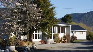 A two-story building with a large porch and a stone wall. - Apostles View Motel (Greymouth)