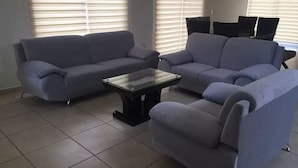 A living room with two grey sofas, a glass coffee table, and a TV stand with a flat-screen TV.