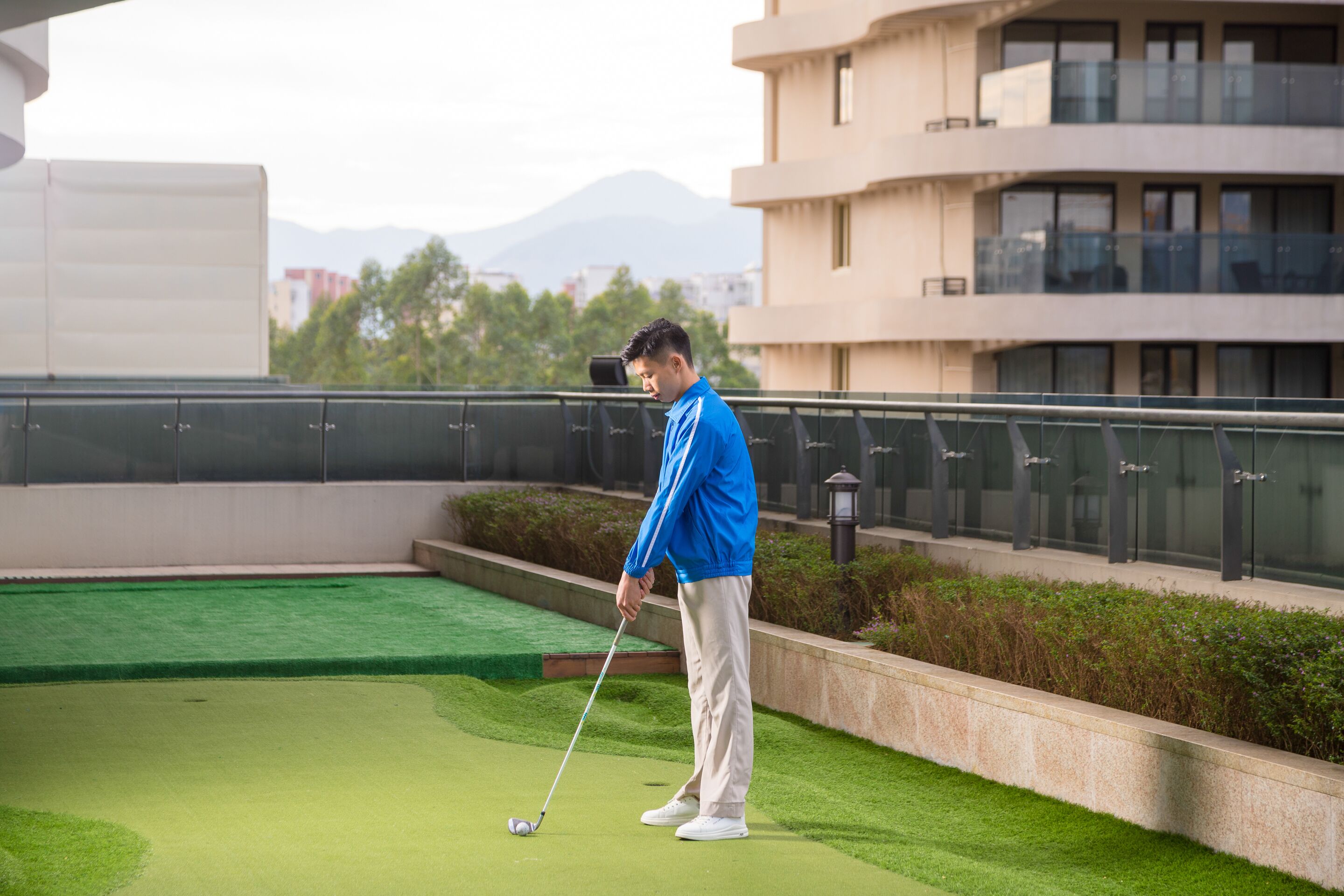 A person playing golf on a green with a building in the background.