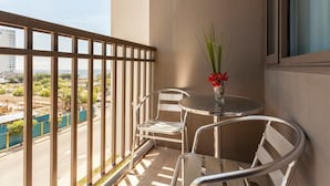 A balcony with a view of a cityscape, a round table, two chairs, and a vase with red flowers. - Francisco Place (Pasay)