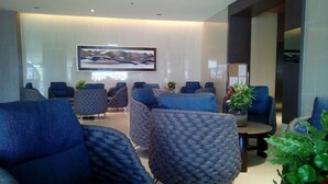 A modern lobby with blue upholstered seating, a large abstract painting on the wall, and a small table with a plant. - Francisco Place (Pasay)