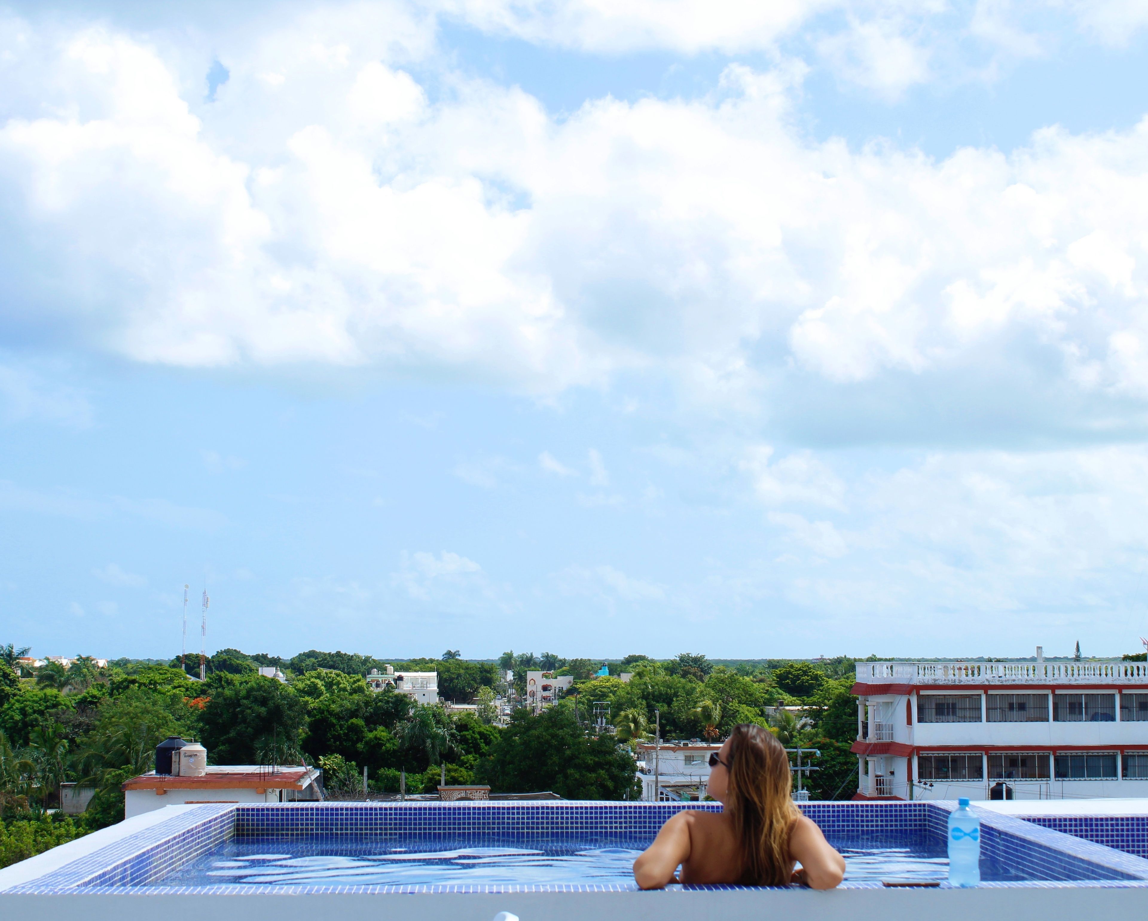 A rooftop swimming pool with a view of the cityscape and buildings in the background.