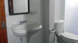Ein Badezimmer mit einem Waschbecken auf Säule, einer Toilette und einem Spiegel.