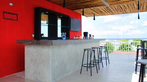 Ein moderner Barbereich mit roter Wand, Holzboden und Blick auf den Ozean.
