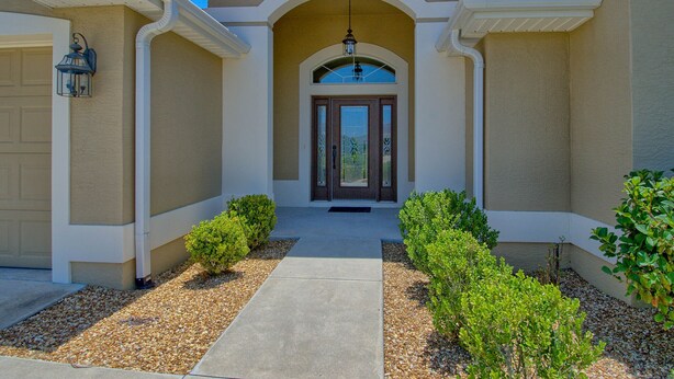A two-story house with a central entrance, a covered porch, and a driveway leading to the garage. - BEAUTIFUL HOME GAS GOLF CART NEAR BROWNWOOD PADDOCK SQ    THE VILLAGES FL (The Villages)