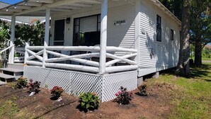 A white house with a porch, a number sign, and a lattice fence. - Eagle Harbor- Harbor View: Soak Up the Sun at a Beachside Cottage This Summer (Eagle Harbor)