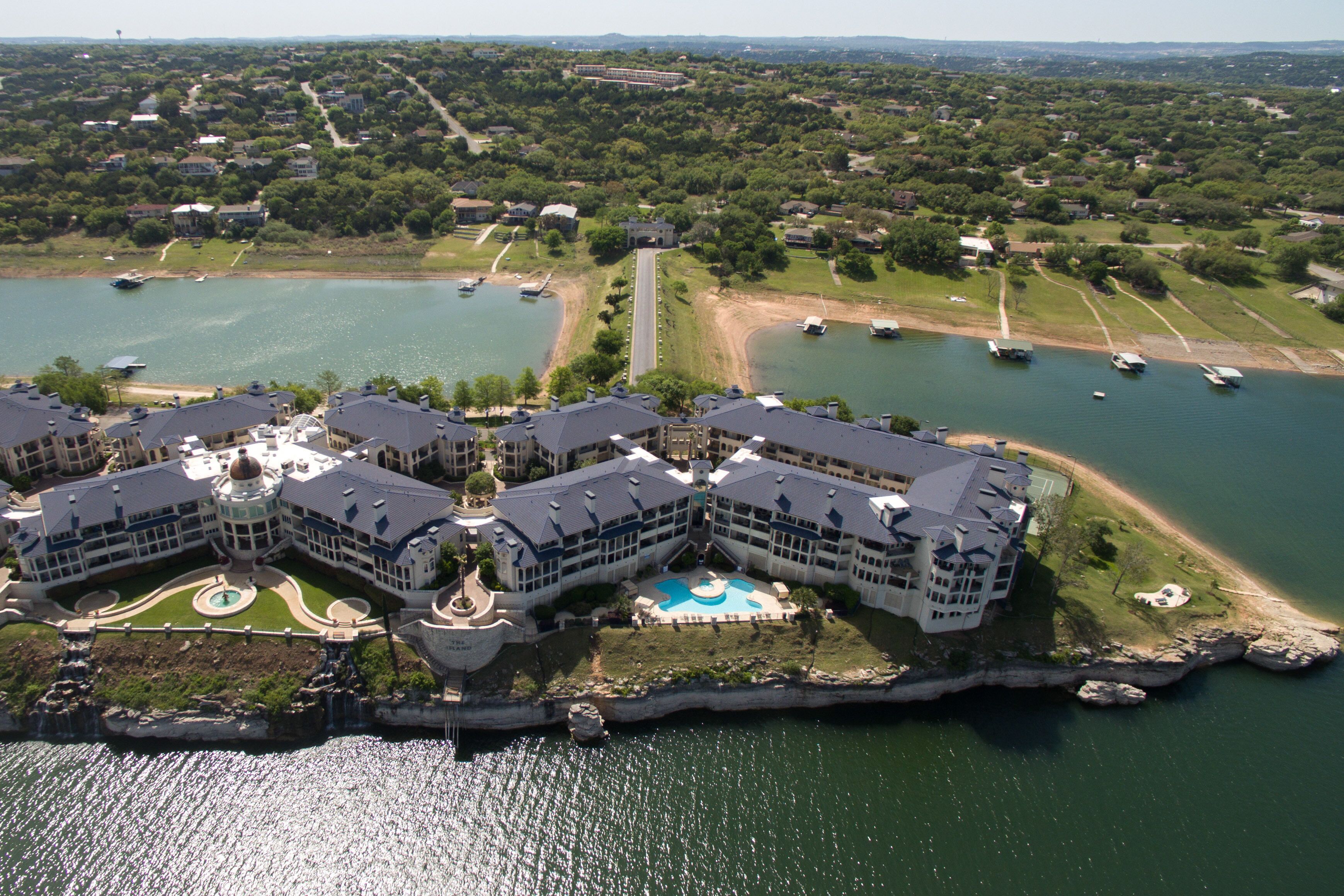 A large hotel with multiple buildings, a central pool, and a waterfront location with boats.