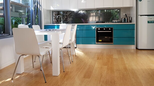 A modern kitchen with white and teal cabinetry, a built-in oven, and a refrigerator. - Beautiful Beach-side cottage with lap pool in North Maroubra close to Coogee (Maroubra)