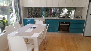 A modern kitchen with teal cabinets, a white countertop, and a built-in oven. - Beautiful Beach-side cottage with lap pool in North Maroubra close to Coogee (Maroubra)