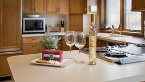 A kitchen with wooden cabinets, a microwave, a stove, and a bottle of peach wine. - Spacious Home nestled along the Blackberry River in Northwest CT (East Canaan)