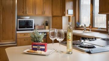 Une cuisine avec des meubles en bois, un four à micro-ondes, une cuisinière et une bouteille de vin à la pêche.