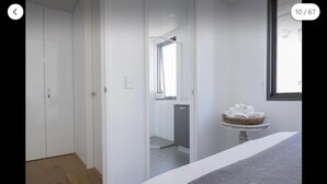 A modern hotel room with a large wardrobe, a small bathroom, and a view of the city. - New apartment in the historic West End close to cafes bars and restaurants.  (Fremantle)