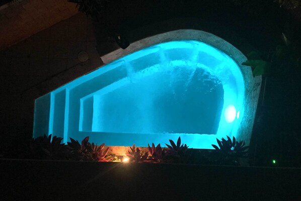 A swimming pool with a curved edge and a blue light.