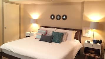 A neatly made bed with white linens, two bedside tables with lamps, and decorative wall mirrors.