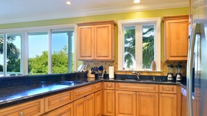 A kitchen with wooden cabinets, a black countertop, and a stainless steel refrigerator. - Waterfront Home in Key Cove Landings (Key West)