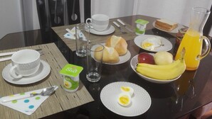 A dining table set with breakfast items including bread, eggs, and fruit, with a pitcher of orange juice and a cup of coffee. - Casa Dulce Casa (Lima)