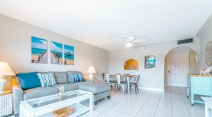 Un salon avec un canapé, une table basse et des œuvres d’art accrochées au mur.