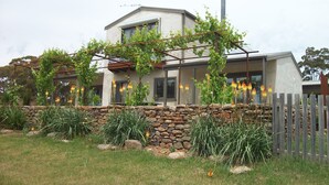 A modern two-story house with a stone wall and a wooden fence. - Casina Marcella - country house (Basalt)