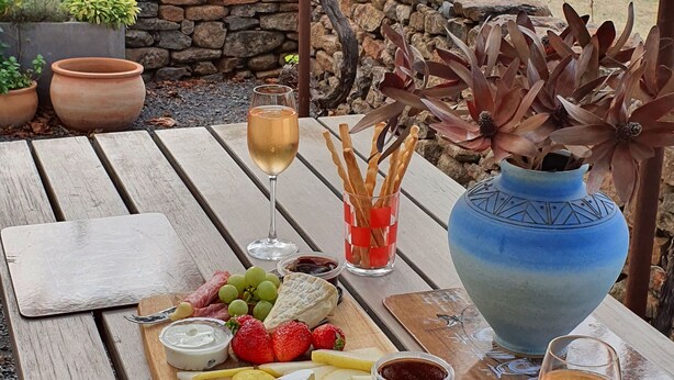 A picnic setup with a wooden table, a cheese board, grapes, strawberries, crackers, and two glasses of wine. - Casina Marcella - country house (Basalt)