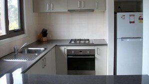 A compact kitchen with white cabinets, a stainless steel sink, a gas stove, and a built-in oven. - Casina Marcella - country house (Basalt)