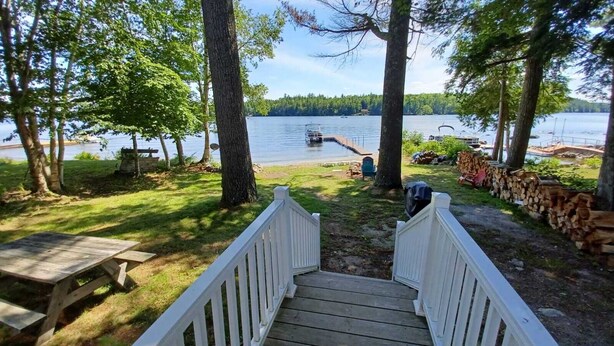 A wooden deck leading to a dock by a lake, surrounded by trees and a picnic table. - Perfect Lakefront Getaway ~ Beautiful Private Setting!  (Dedham)