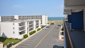 A multi-story hotel with a parking lot and a view of the beach.