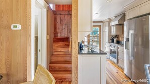 A modern kitchen with wooden flooring, a stainless steel refrigerator, and a built-in oven.