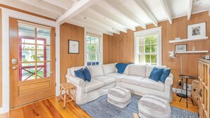 A spacious living room with a large sectional sofa, a small stool, and a patterned rug.