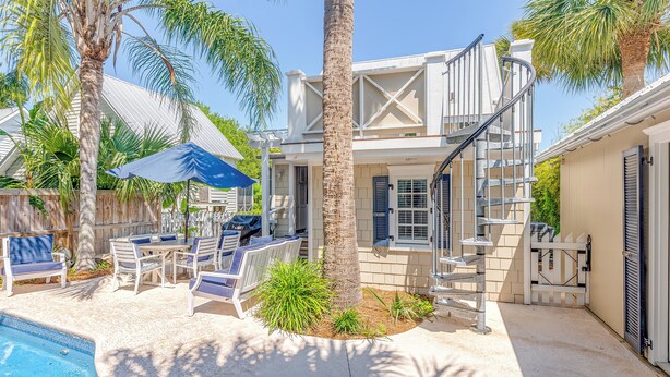 A poolside area with a staircase, outdoor furniture, and palm trees.