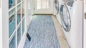 A laundry room with a washing machine, dryer, and a glass-enclosed cabinet.